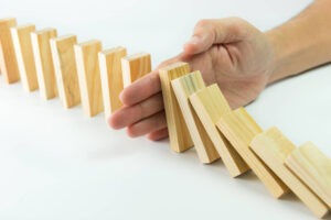 Metaphor for Food Waste Prevention- Solution concept with hand stopping wooden blocks from falling in the line of domino