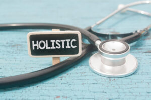 Stethoscope and wooden tag written holistic over wooden background